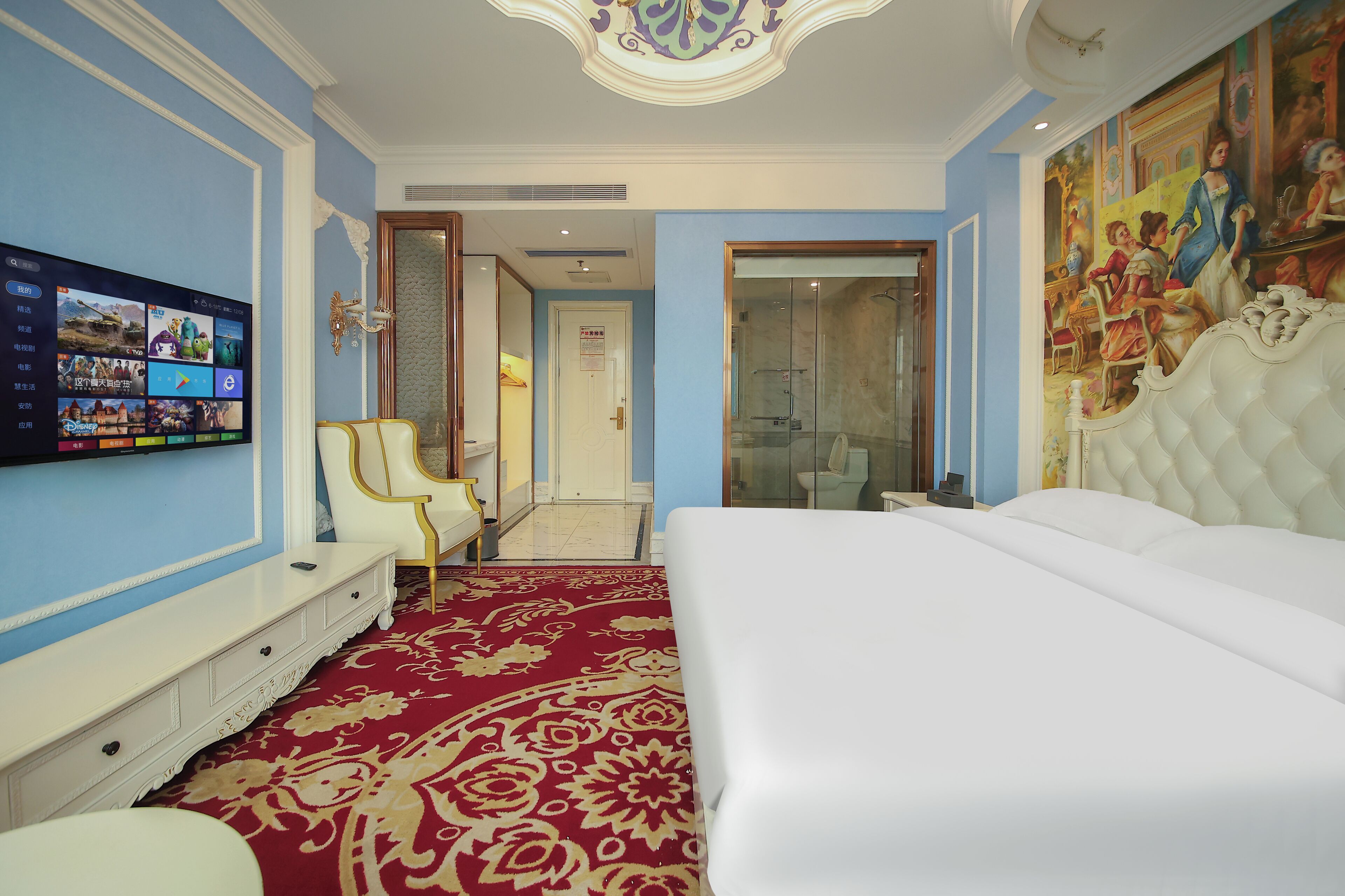 A hotel room with a large bed, a television mounted on the wall, a red patterned carpet, and a painting on the wall.