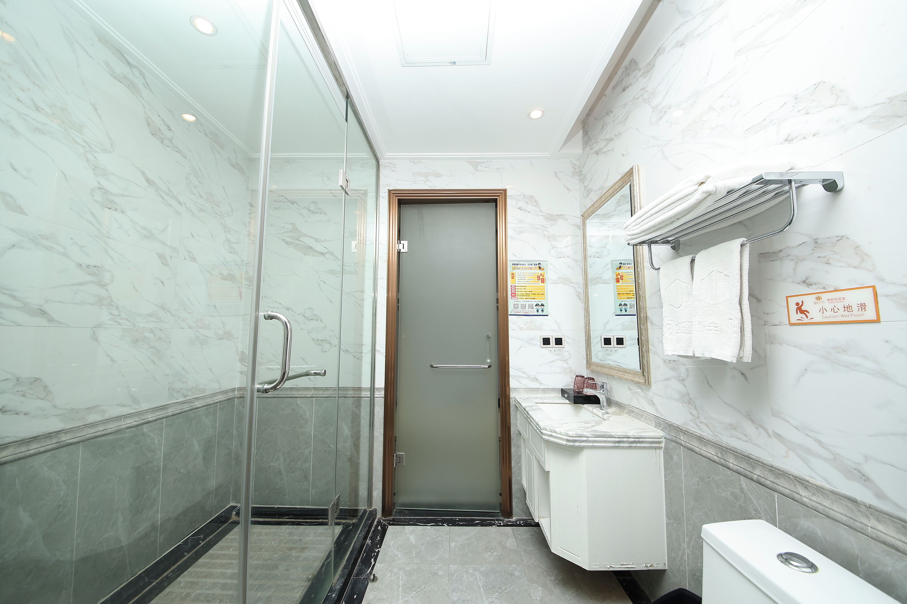 A bathroom with a glass shower enclosure, a white sink, and a toilet.