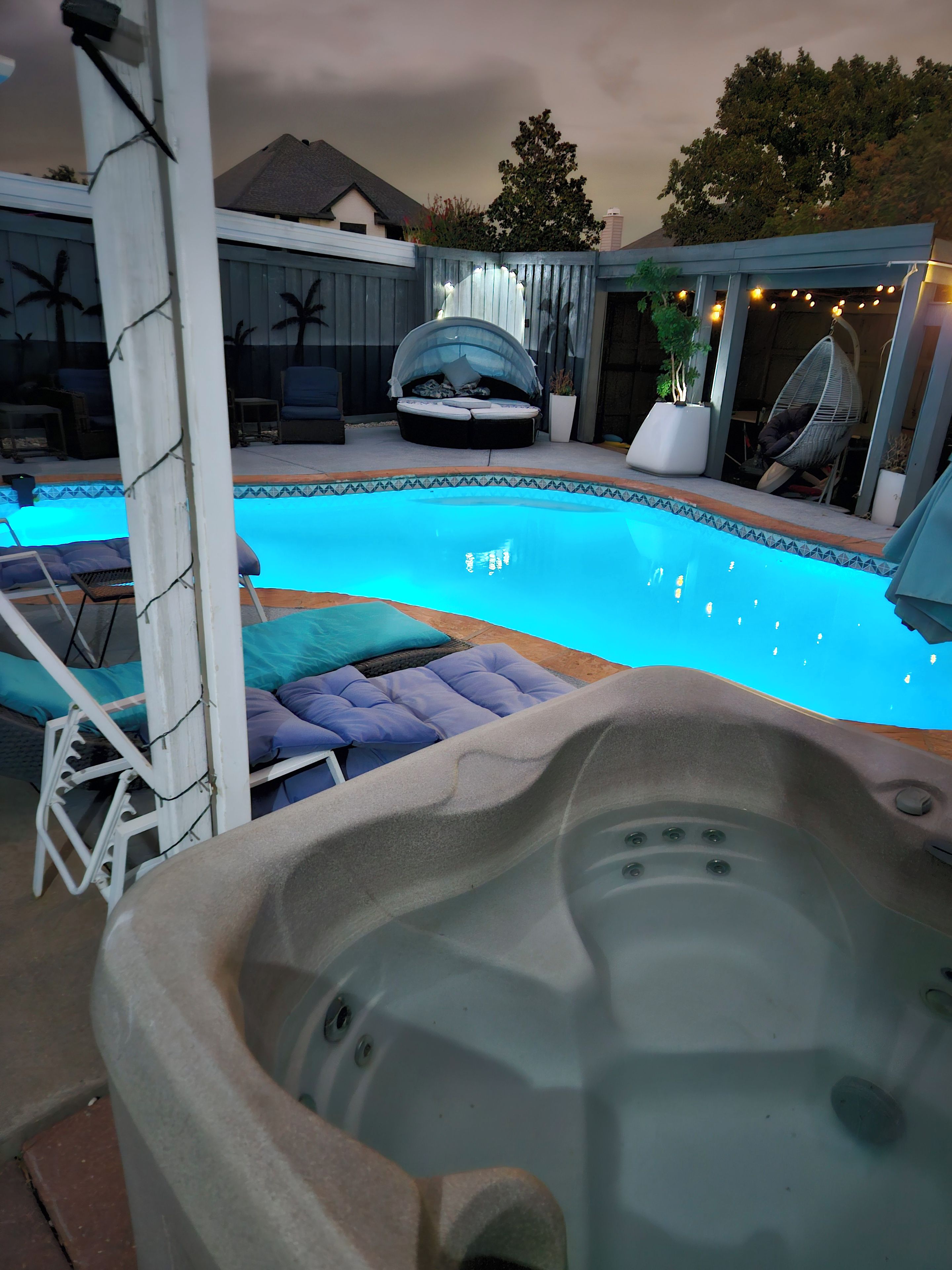 A swimming pool with lounge chairs and a hot tub.
