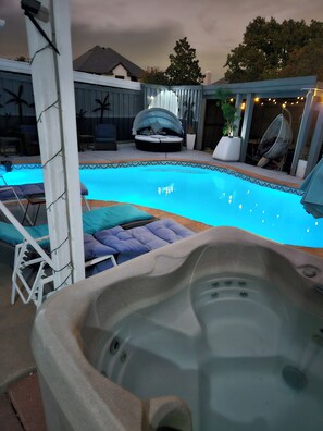 A swimming pool with lounge chairs and a hot tub.