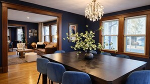 A dining area with a dark wooden table, blue upholstered chairs, and a vase with flowers. - Prestigious Milton Designer Home (Milton)