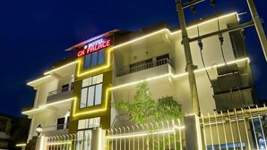 A hotel with a modern facade, illuminated signage, and a gated entrance. - HOTEL GK PALACE (Guwahati)