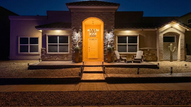 Uma casa de dois andares com uma porta laranja marcante, fachada de pedra e entrada bem iluminada.
