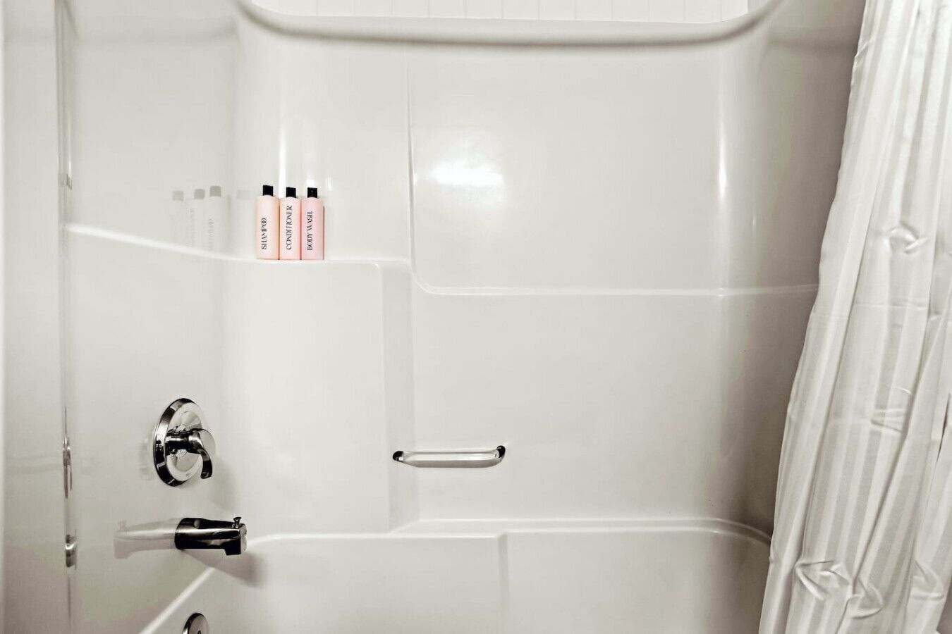 A white bathroom with a shower curtain, a toilet, a sink, and a mirror.