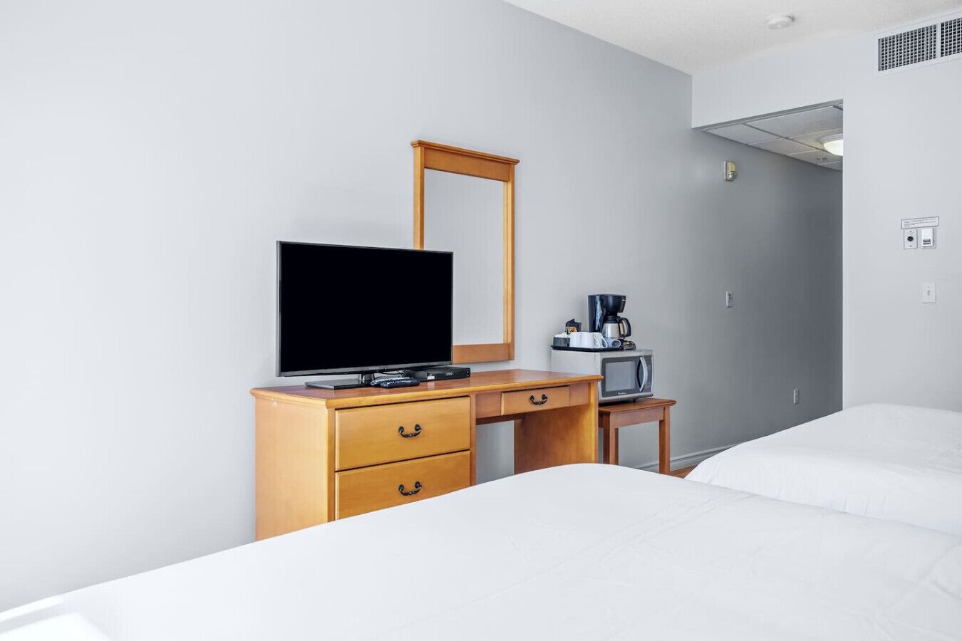 Ein Hotelzimmer mit einem Holztisch, einem Fernseher, einer Kaffeemaschine und einer Mikrowelle.