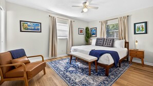 A bedroom with a bed, a bench, a chair, a nightstand, and a ceiling fan. - The Terrace Hideaway 3BR WFH, Sleeps 6 (Tampa)