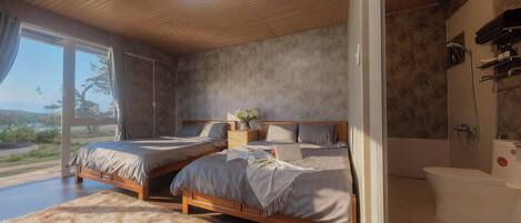 A bedroom with two beds, a large window, a shower, and a view of the outdoors.