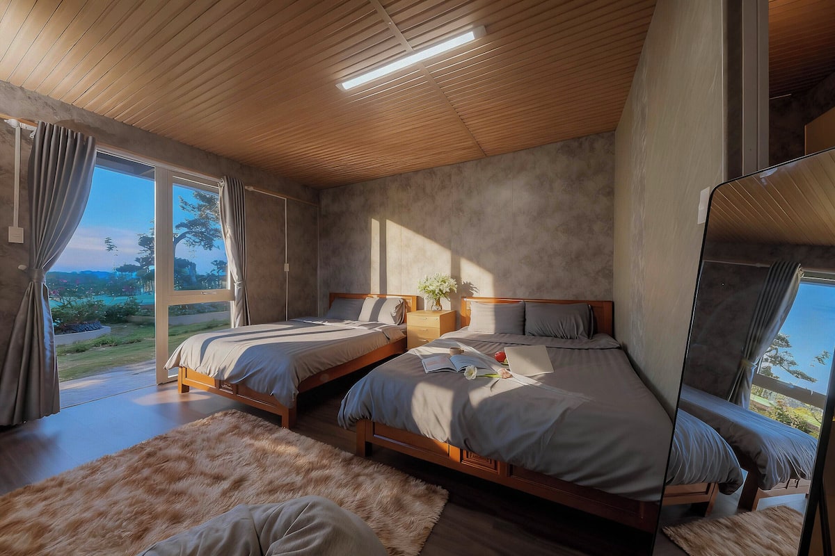 Un dormitorio con dos camas, un espejo grande y vistas al exterior.