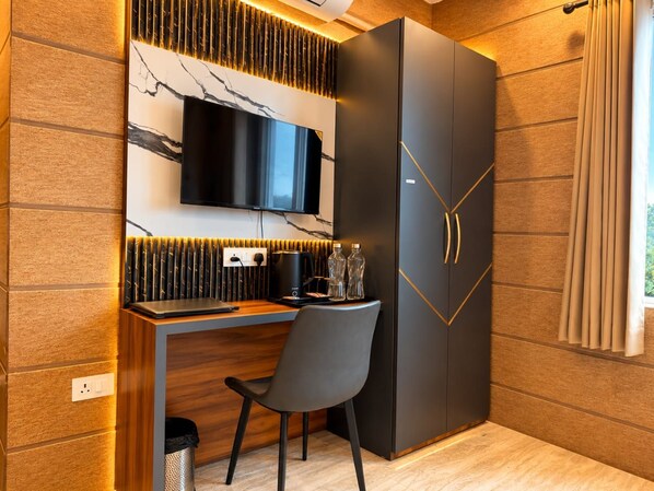 A modern room with a built-in desk, a flat-screen TV, and a wardrobe with a geometric design. - Hotel Celestial Ganges (Rishikesh)