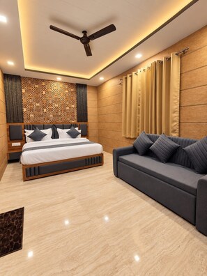 A modern bedroom with a bed, a sofa, a ceiling fan, and a decorative wall panel. - Hotel Celestial Ganges (Rishikesh)