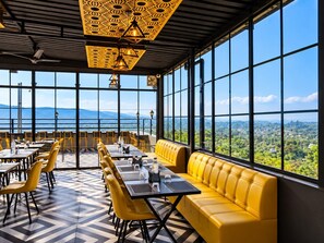 A restaurant with a terrace, large windows, and a view of the landscape. - Hotel Celestial Ganges (Rishikesh)