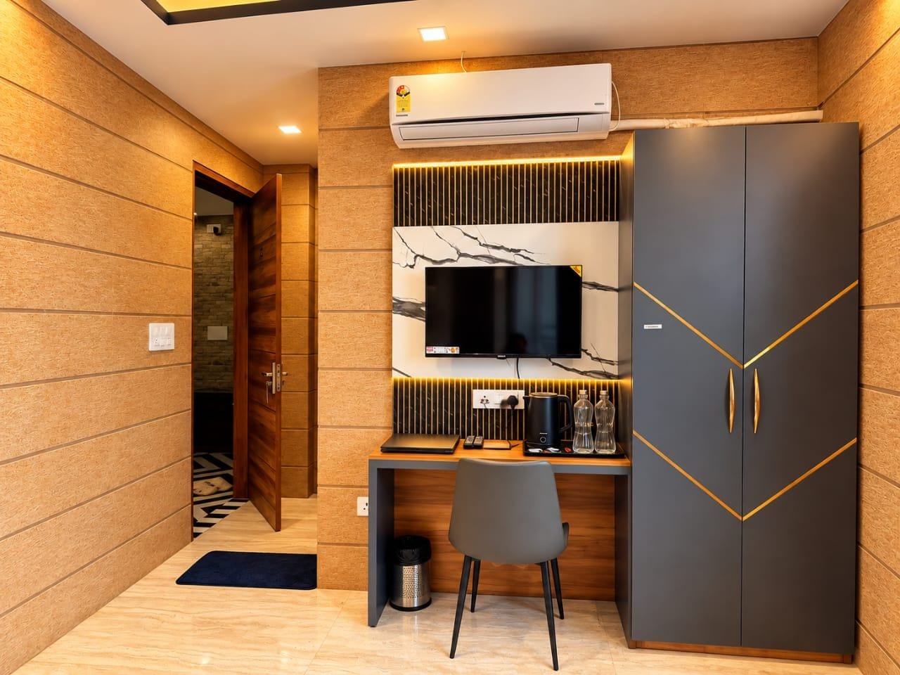 Una habitación moderna con una pared de madera, un escritorio con televisor de pantalla plana, un armario y un equipo de aire acondicionado.