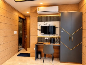 A modern room with a wooden wall, a desk with a flat-screen TV, a wardrobe, and an air conditioning unit. - Hotel Celestial Ganges (Rishikesh)