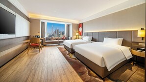 A hotel room with two beds, a sofa, a desk, a chair, and a large window with a city view. - ECHENG Hotel (Nanning Mixc City Exhibition Branch) (Nanning)