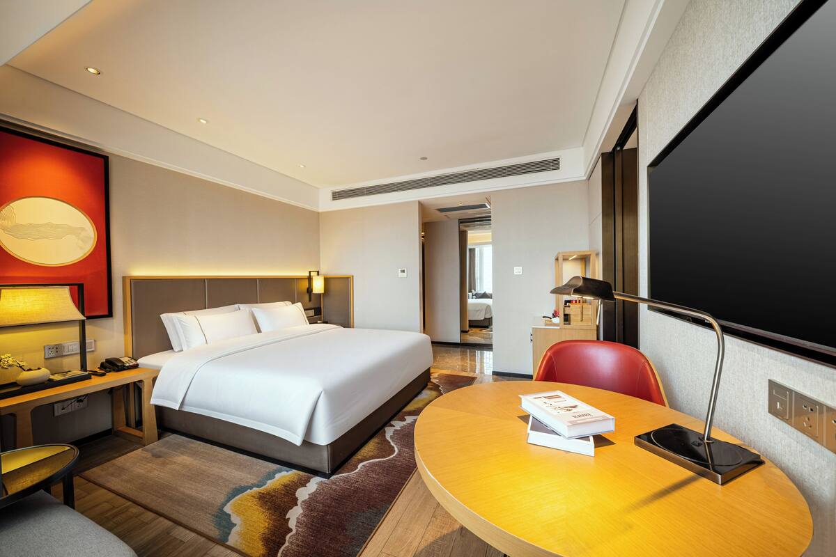 Una habitación de hotel con cama, escritorio, silla y televisor.