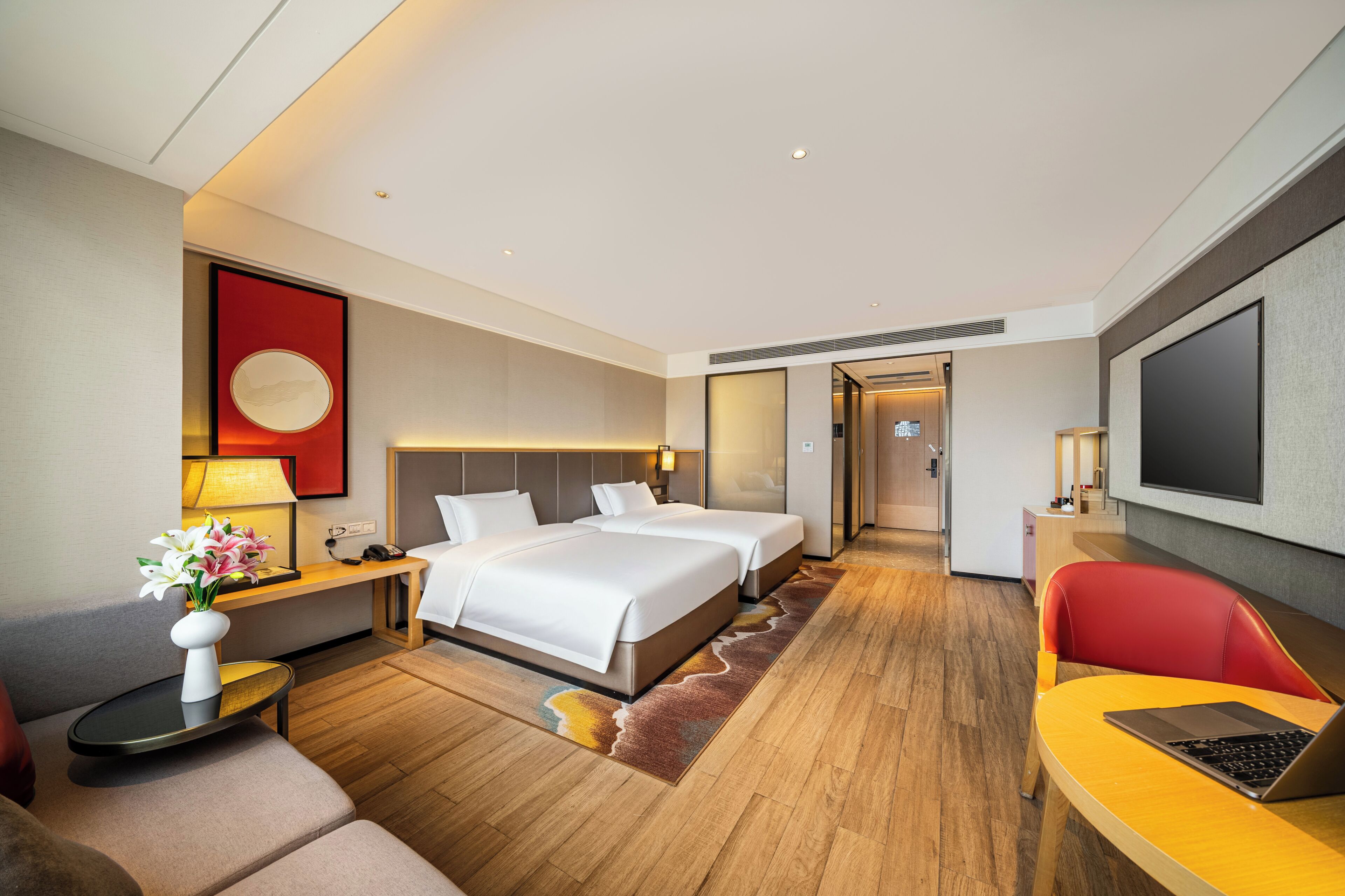 Habitación de hotel con cama, escritorio, silla, televisor y baño.