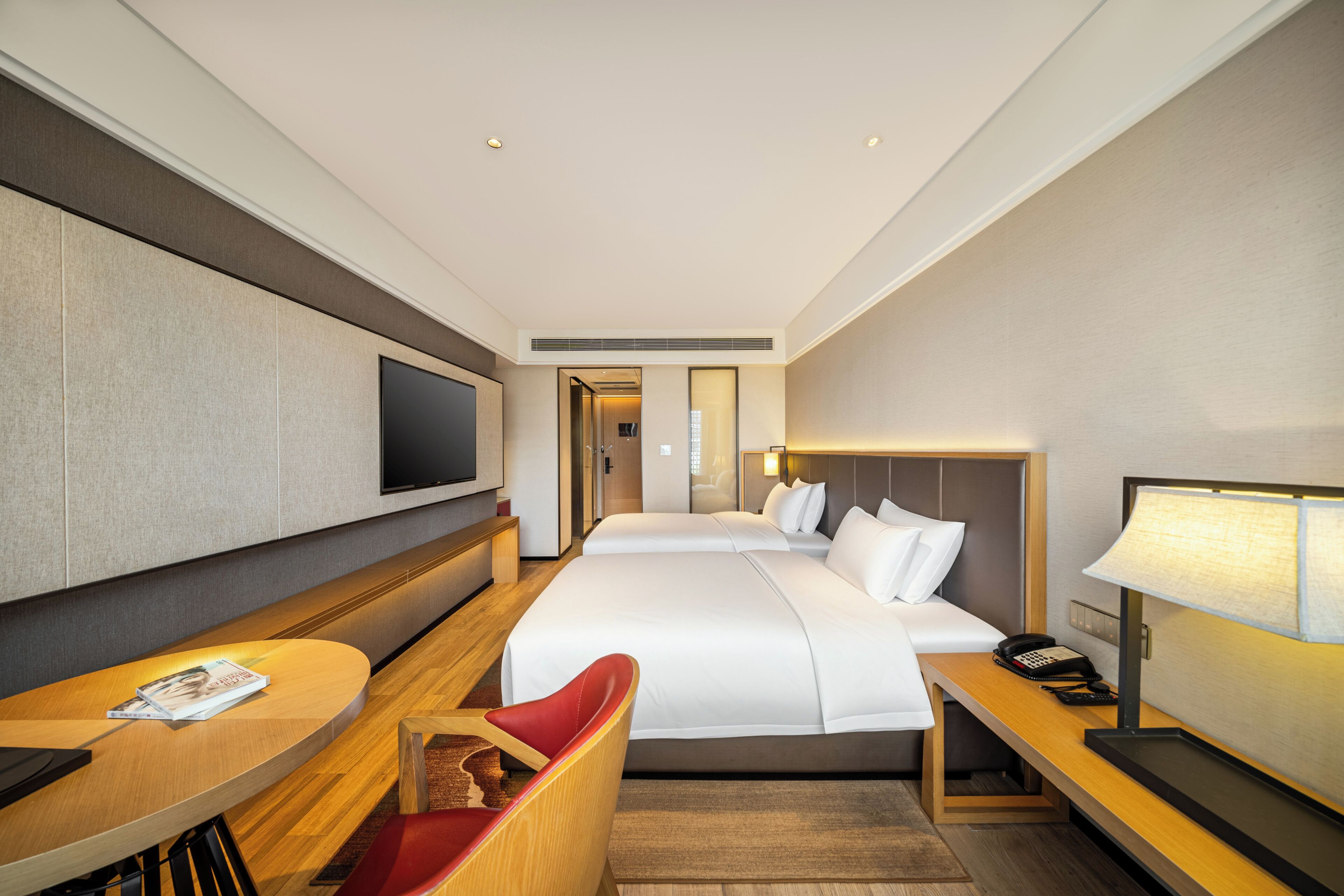 Habitación de hotel con una cama grande, un escritorio con silla, un televisor y una mesita de noche con lámpara.