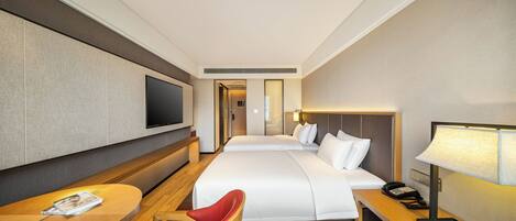 Habitación de hotel con una cama grande, un escritorio con silla, un televisor y una mesita de noche con lámpara.