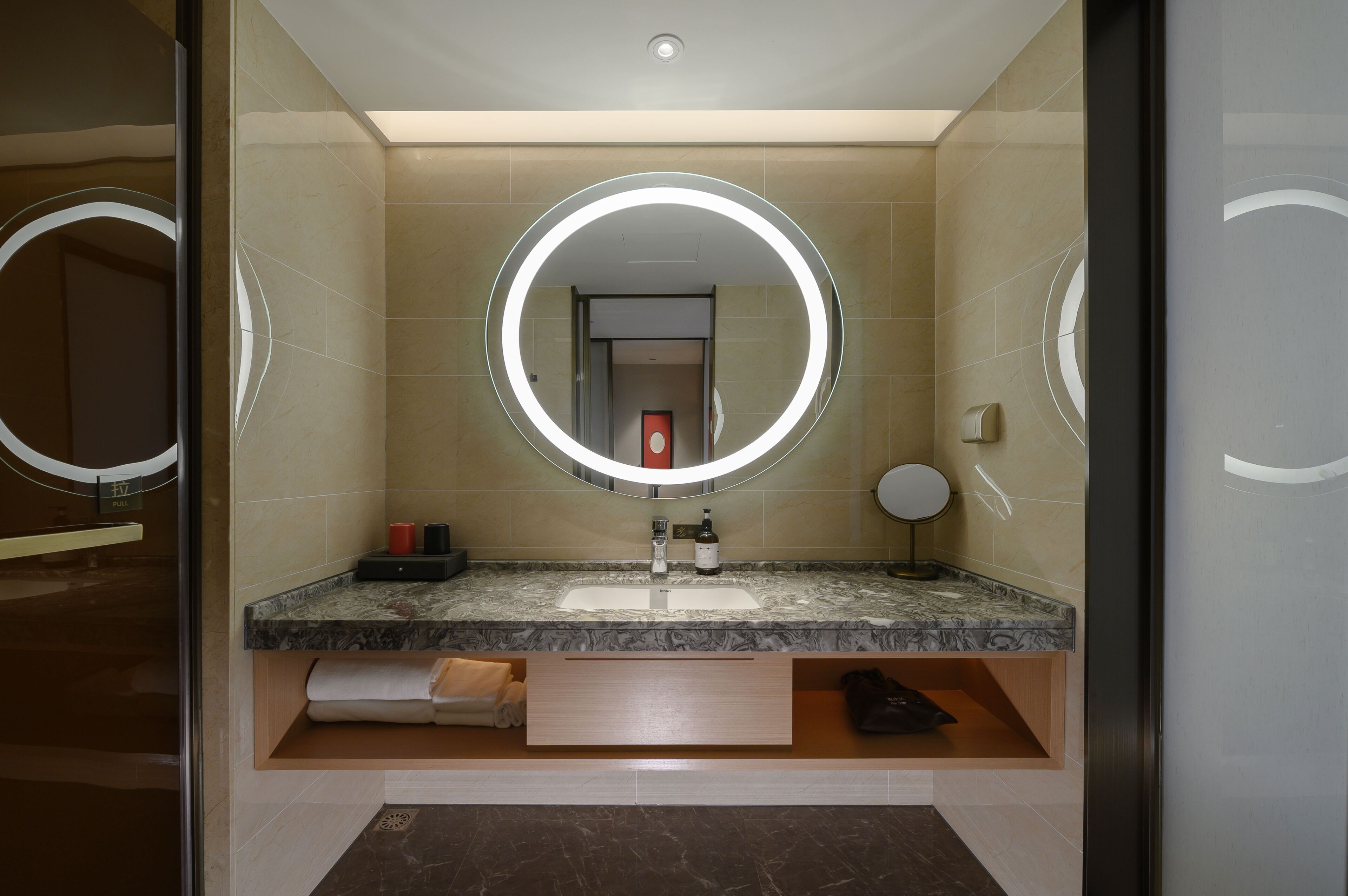 Un baño moderno con un espejo grande, dos lavamanos y un perchero para toallas.