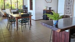 Un'ampia stanza con soffitto in legno, un'area pranzo con tavolo e sedie, e una pianta in vaso su un bancone di legno.