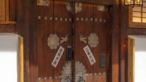 A wooden double door with metal reinforcements and a sign above it. - Damitory inn Dongmyo (Seoul)