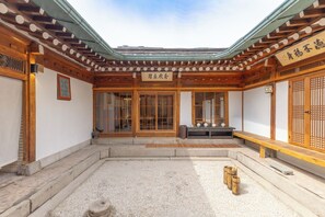 A traditional Japanese building with a wooden exterior, a tiled courtyard, and a sign with Japanese characters.