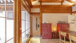 A wooden interior with a sliding glass door, a red cabinet, and a table. - Damitory inn Dongmyo (Seoul)