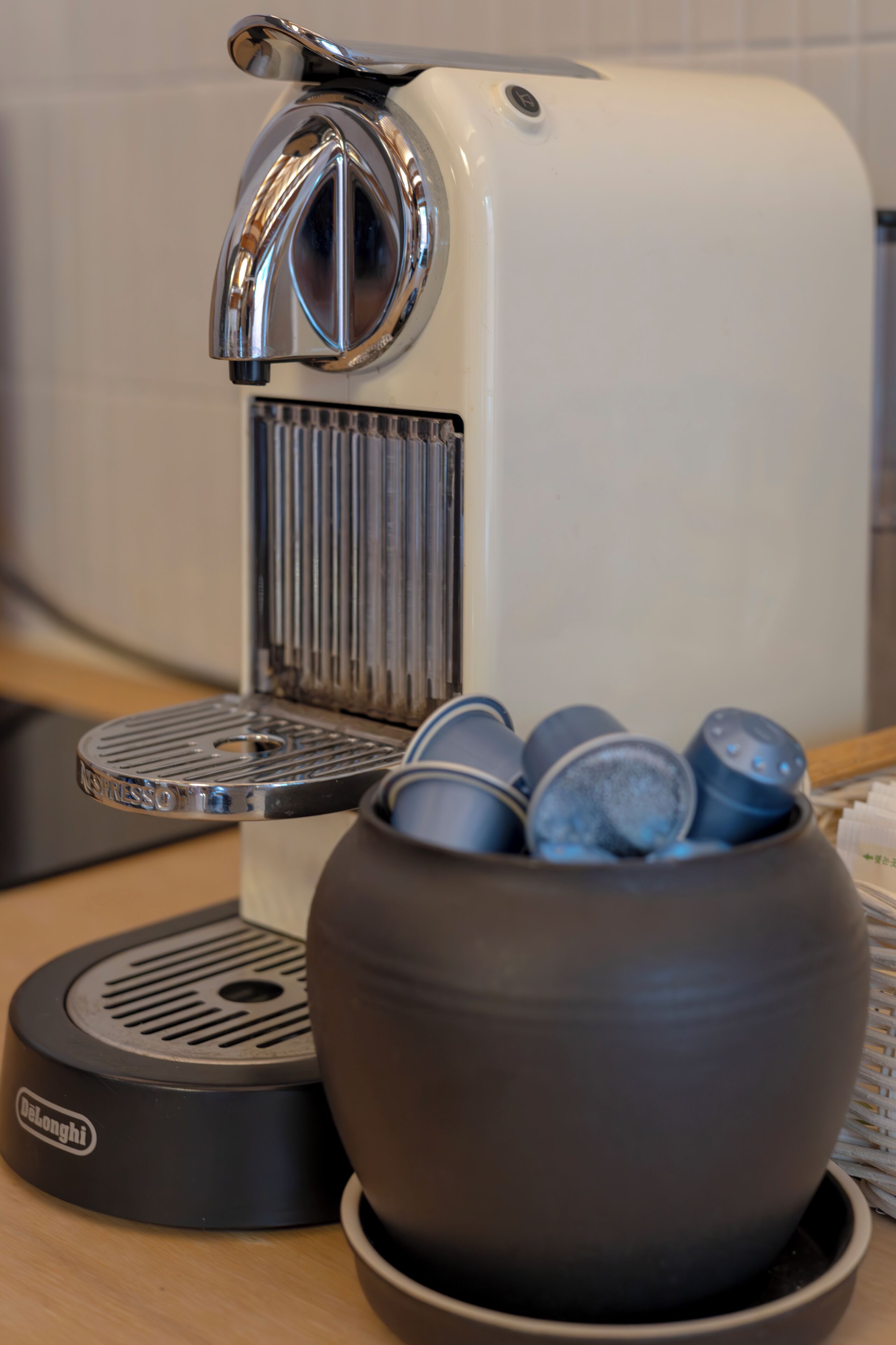 A coffee machine with a cup holder and a bowl of coffee pods.