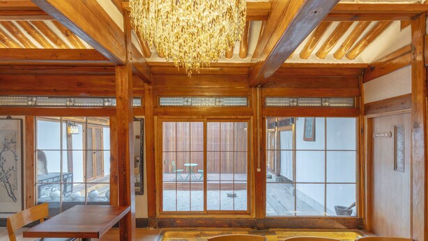 A wooden interior with a dining area, large windows, and a chandelier. - Damitory inn Dongmyo (Seoul)