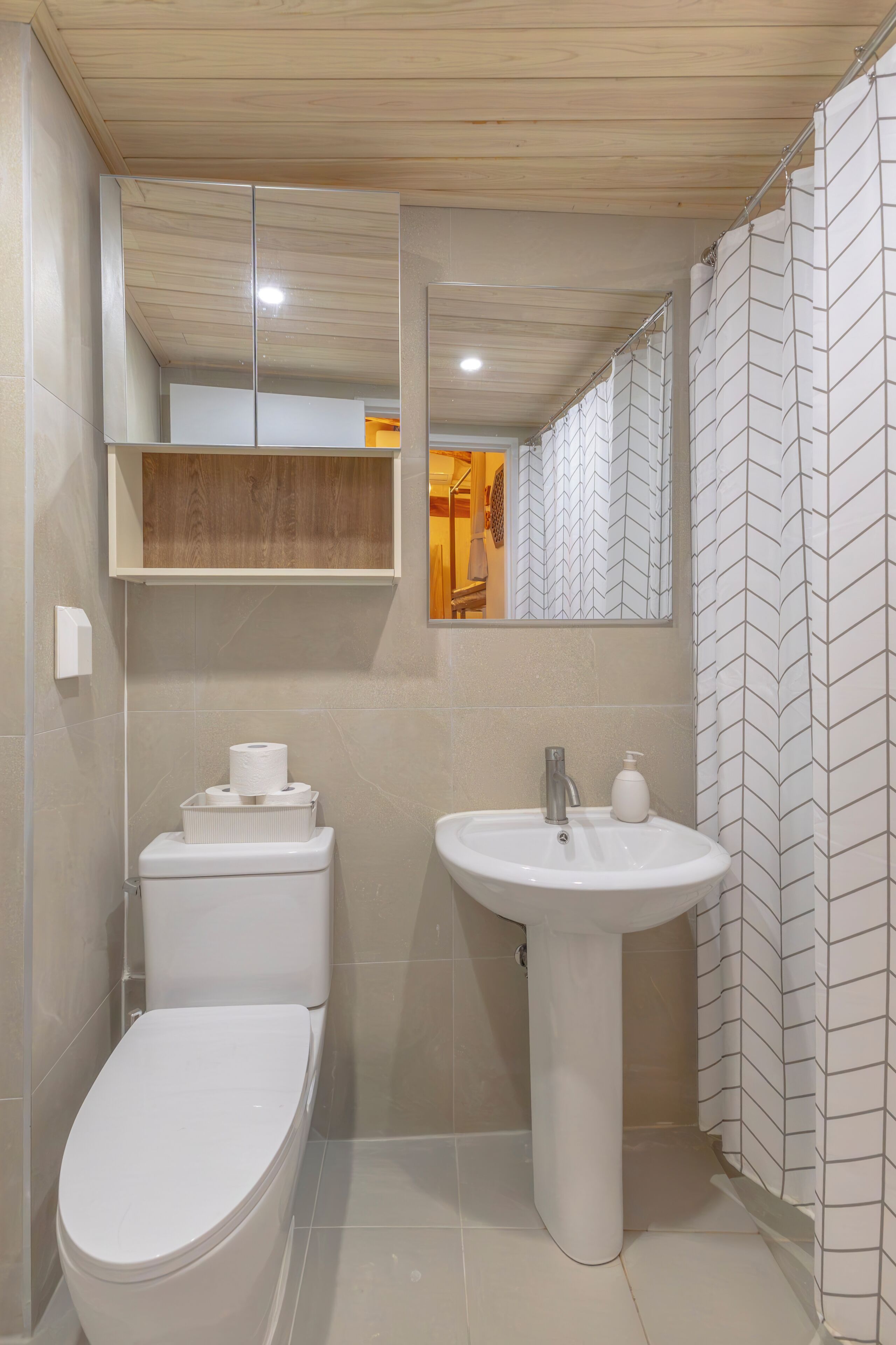 A modern bathroom with a toilet, sink, mirror, and shower curtain.