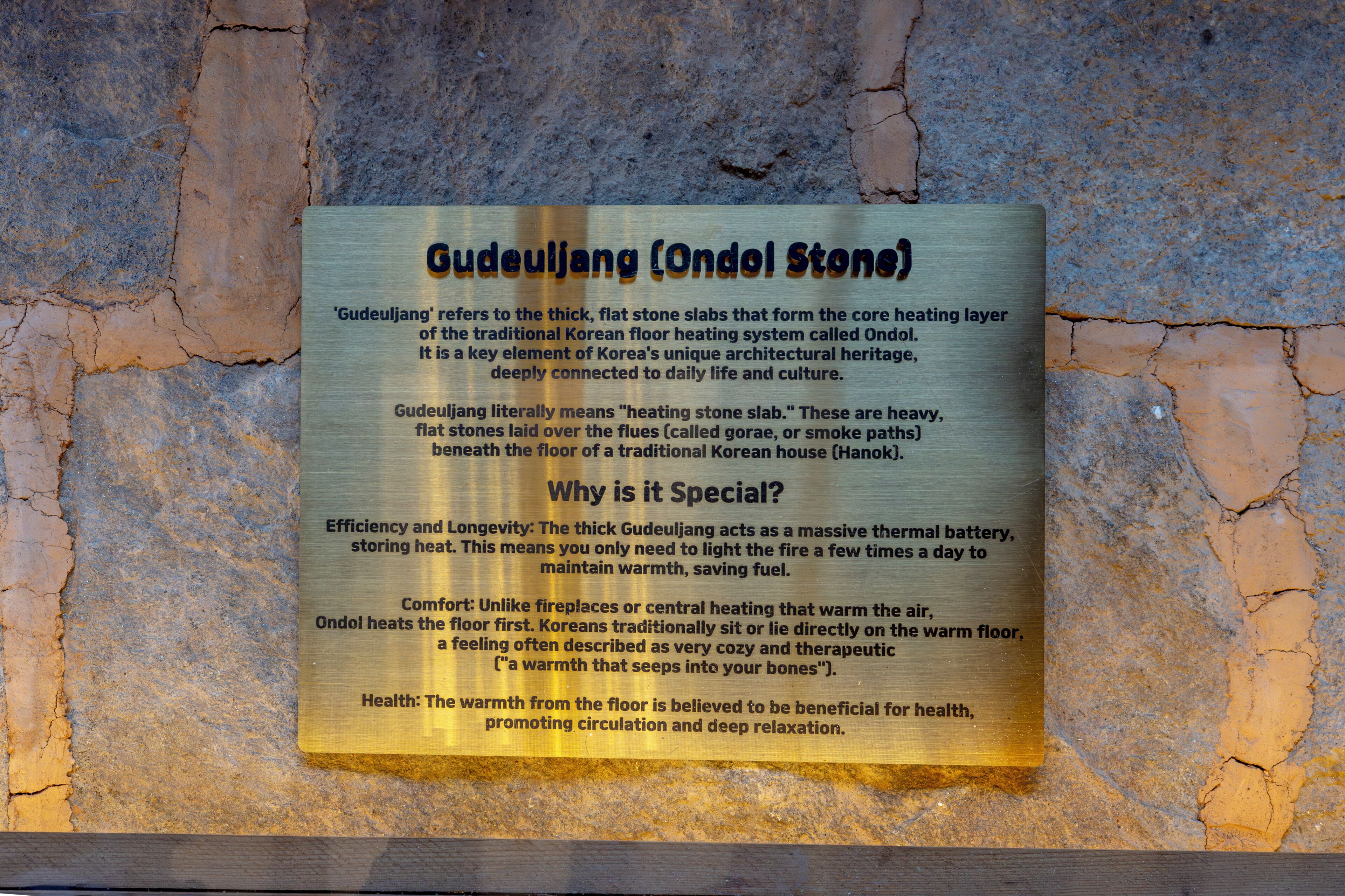 A plaque describing Gudeuljang (Ondol Stone) with text on a stone wall background.