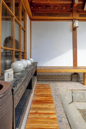 A traditional Japanese interior with a wooden bench, a tiled floor, and a display of white ceramic bowls.