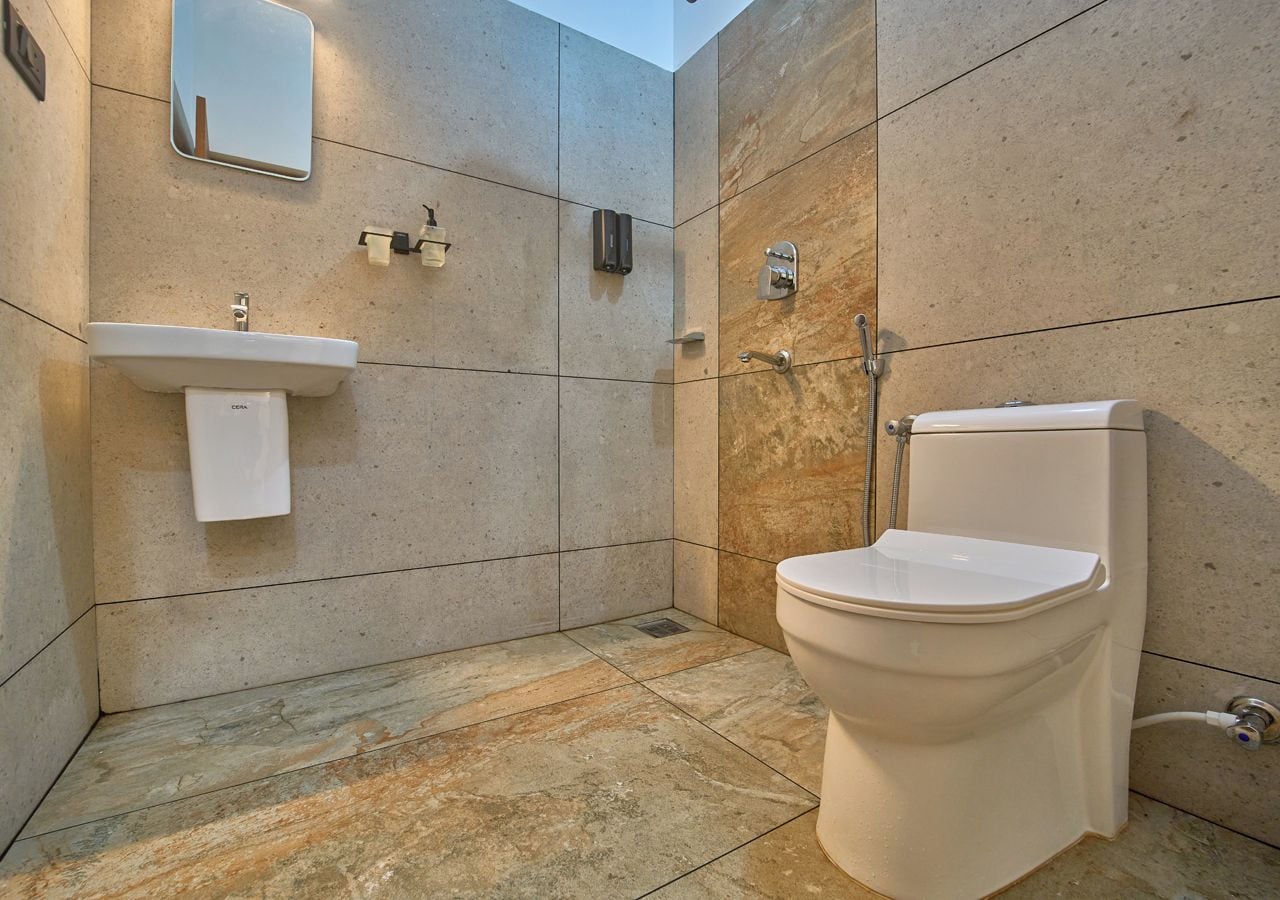 A bathroom with a toilet, sink, and mirror.