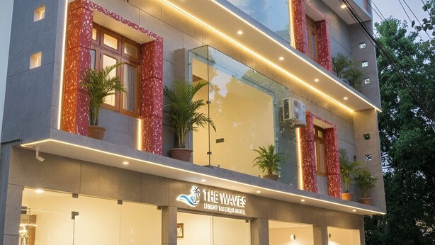 Un hôtel moderne avec une façade en verre, des balcons ornés de touches de rouge et une Mercedes-Benz garée devant.