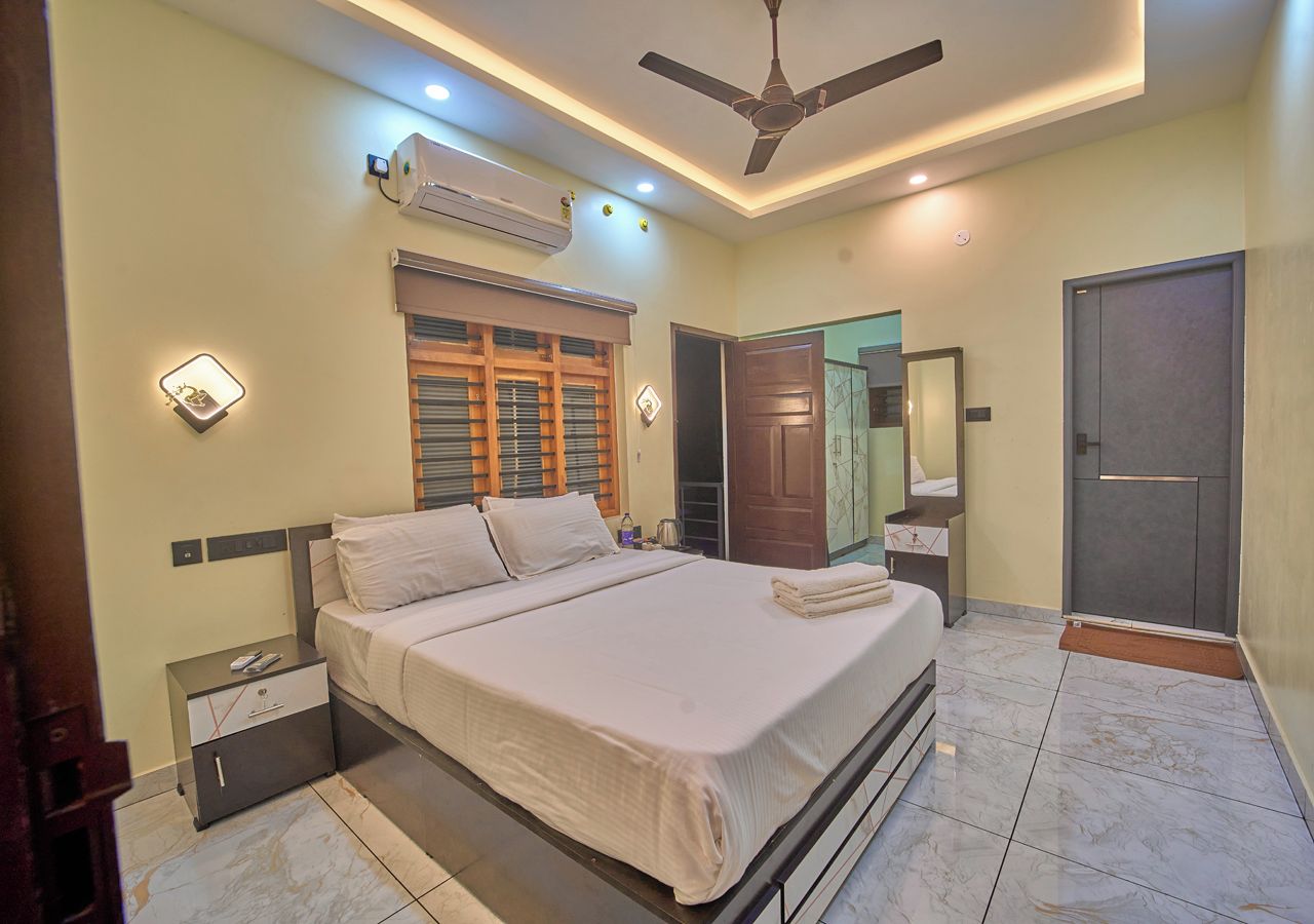 Quarto com cama, mesas de cabeceira, guarda-roupa, espelho e ventilador de teto.