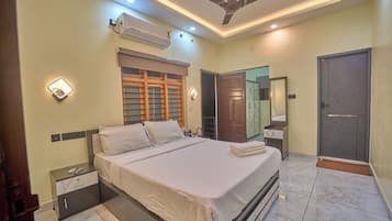 Quarto com cama, mesas de cabeceira, guarda-roupa, espelho e ventilador de teto.