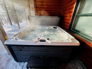Ein Whirlpool in einer Holzhütte mit einer Holzterrasse und einem Fenster.