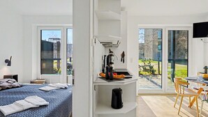 A modern hotel room with a bed, a kitchenette, a dining area, and large windows. - Seemomente 615 (Seenähe) by Interhome (Lembruch)