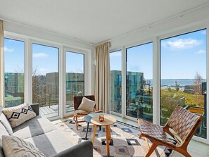 Ein geräumiger Balkon mit großen Fenstern, einer Couch, zwei Stühlen und einem kleinen Tisch.