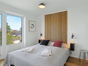 Ein modernes Schlafzimmer mit einem großen Bett, einer Wand aus Holzleisten, einem gerahmten Bild und zwei Nachttischlampen.