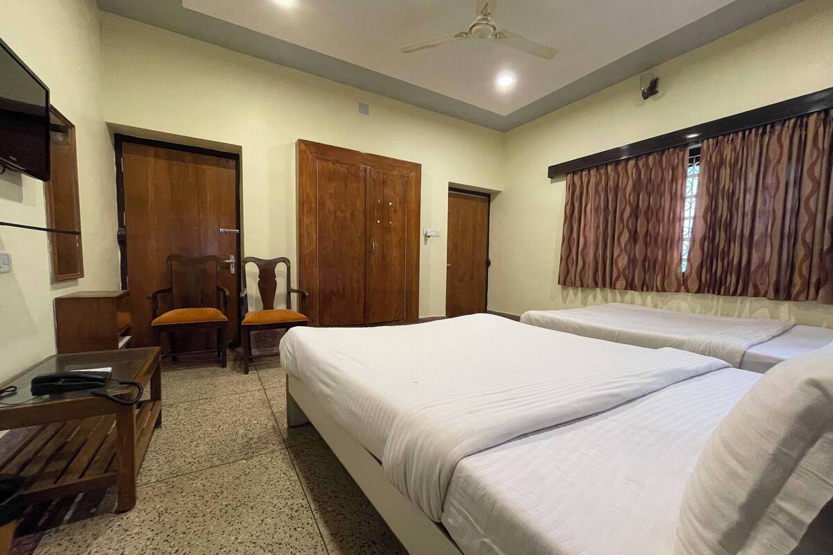 A hotel room with two beds, a desk, a chair, and a wardrobe.