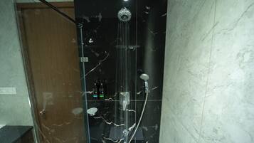Een douche met een handdouche en een wandmengkraan, voor een marmeren wand.