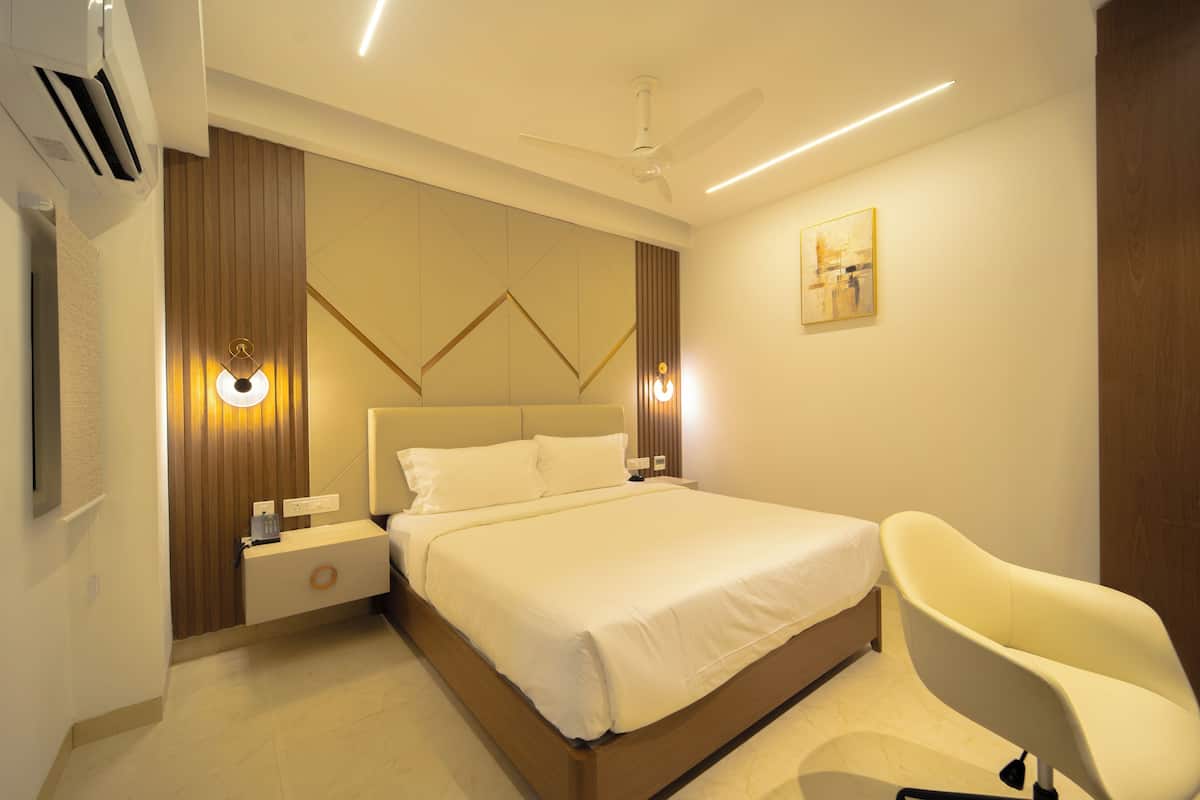 Une chambre moderne avec un grand lit, des tables de chevet, un ventilateur de plafond et une œuvre d’art accrochée au mur.