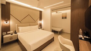 A modern bedroom with a large bed, bedside tables, a desk, and a chair. - Sawariya hotels (Tiruvannamalai)