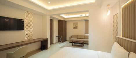 A hotel room with a bed, a desk, a chair, a TV, and a ceiling fan.