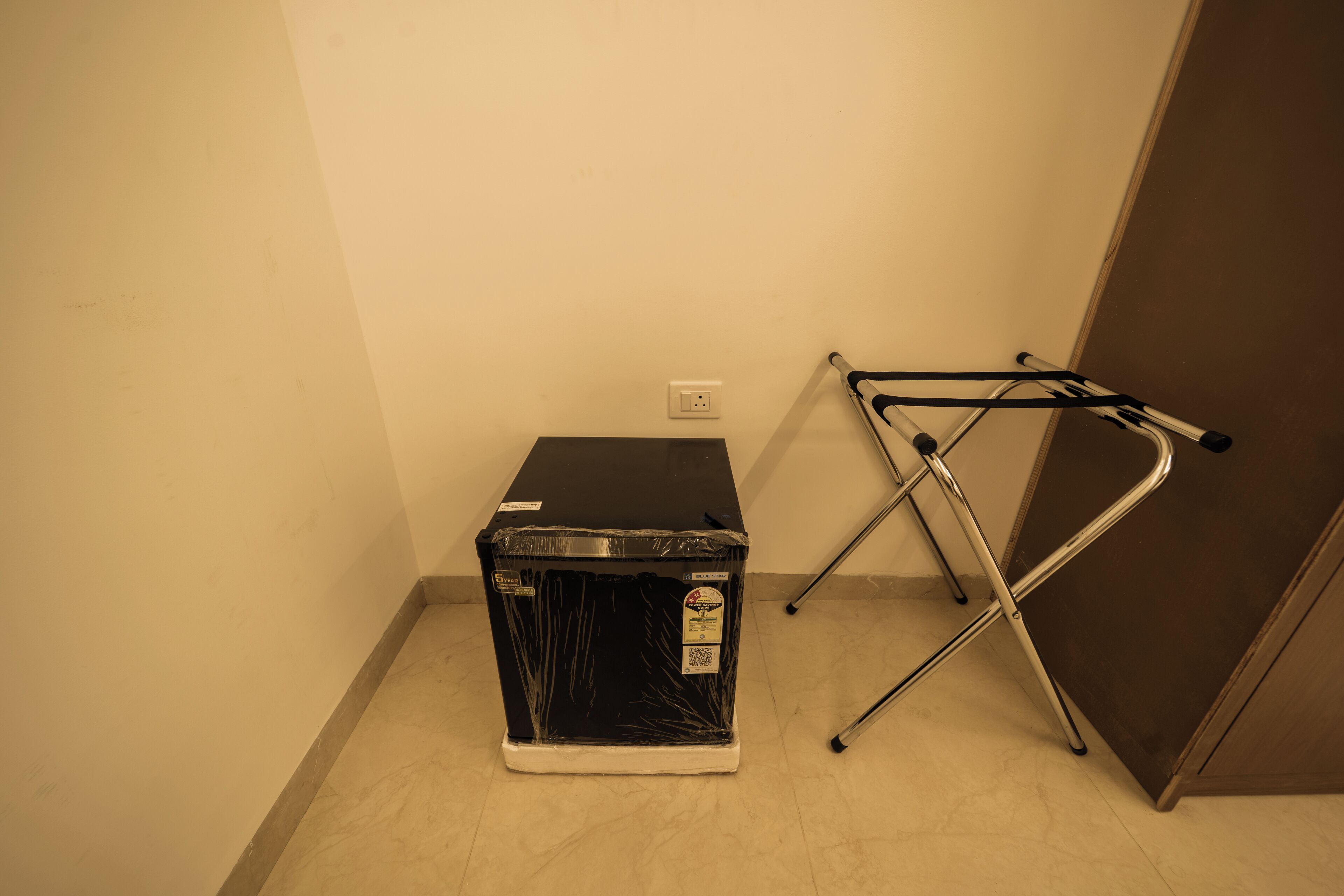 A room with a black appliance, possibly a washer and dryer, and a metal folding chair against the wall.