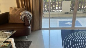 Ein modernes Wohnzimmer mit einem braunen Ledersofa, einem Glastisch und einem schwarz-weißen Streifen Teppich.