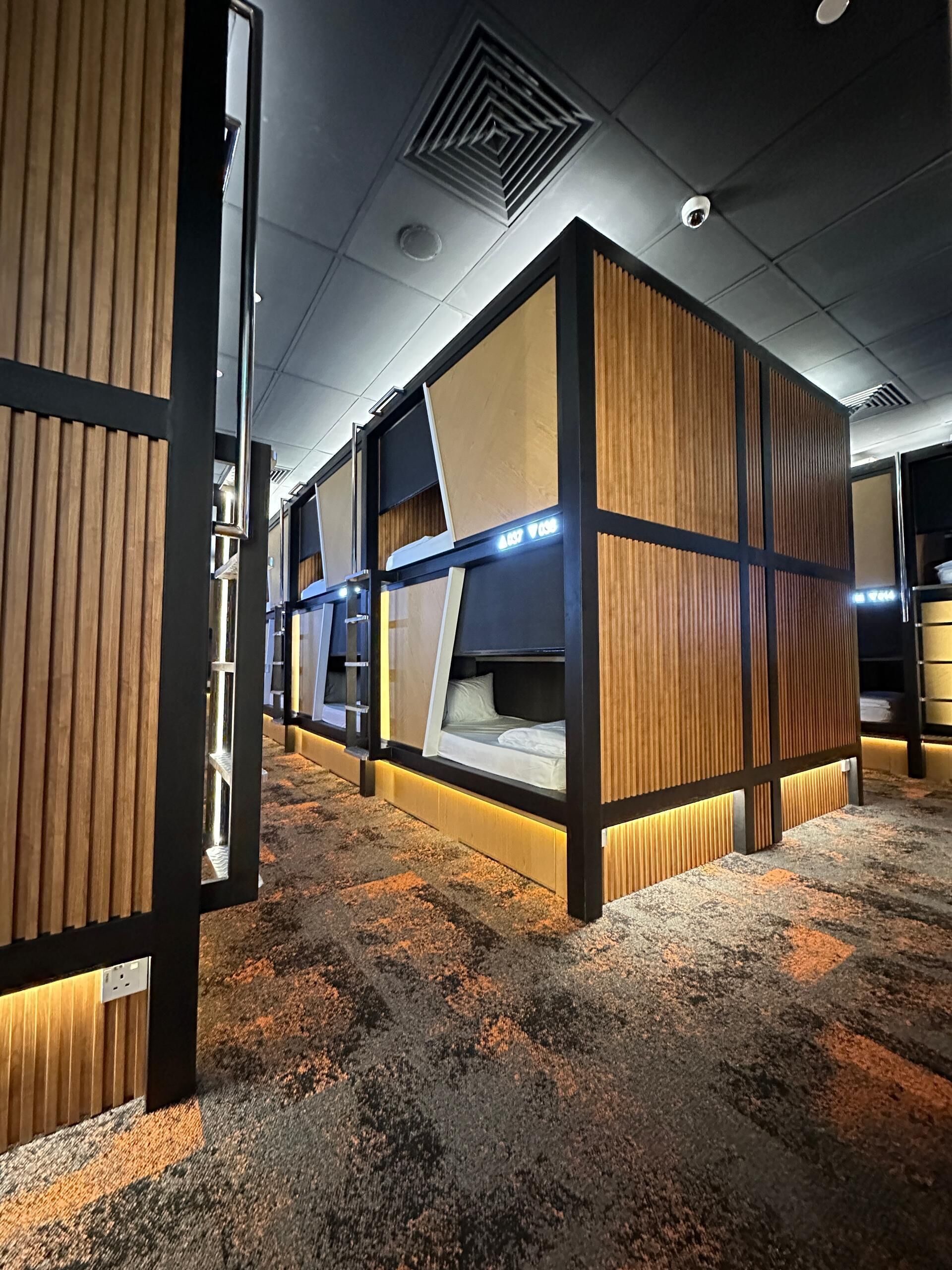 Ein modernes Hotelzimmer mit individuellem Design, ausgestattet mit einem zentralen Bett, das ein hölzernes Kopfteil und eine integrierte Schreibtisch bietet.