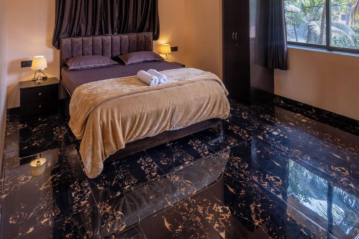A modern bedroom with a bed, dark curtains, a wardrobe, and a window with a view of greenery.