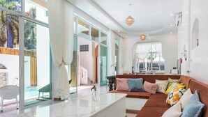 Uma sala de estar moderna com um sofá marrom, uma mesa de centro de vidro e vista para uma piscina.
